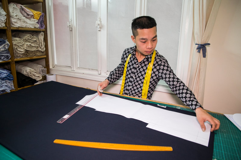 Artisan tailor preparing to cut fabric for a suit. Laying the pattern over the suit fabric.